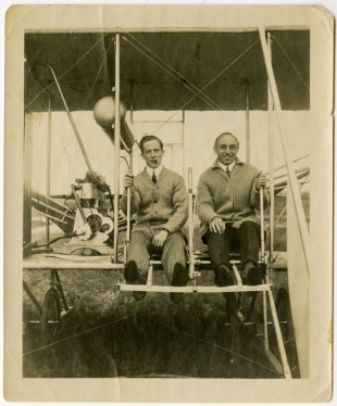 Brown and an unidentified passenger posing in his aero-plane. Many photos of Brown show him with a lit cigar sitting next to the gas tank. 